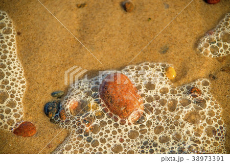 Sandy beach with foam of the surf and pebbles Sandy beach with foam of the surf and pebbles 38973391