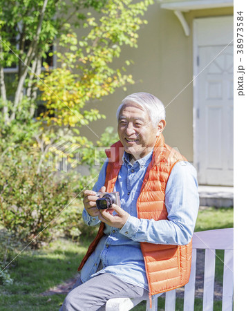 カメラを持ってベンチに腰かけるシニア男性の写真素材