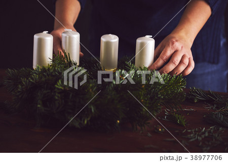 Woman attaches candle holder on a Christmas wreath Woman attaches candle holder on a Christmas wreath 38977706