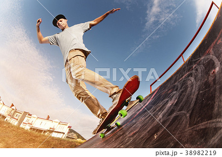 Teen skater hang up over a ramp on a skateboard in 38982219