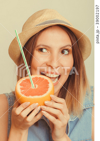 Glad woman in hat eating biting grapefruit. Glad woman in hat eating biting grapefruit. 39002197