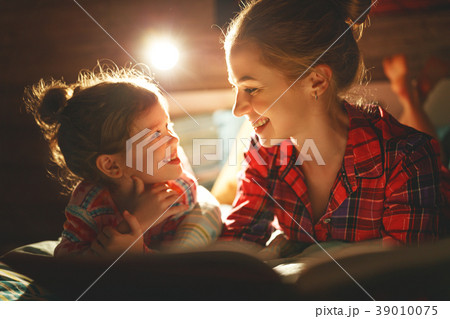 mother and child reading book in bed before going to sleep . 39010075