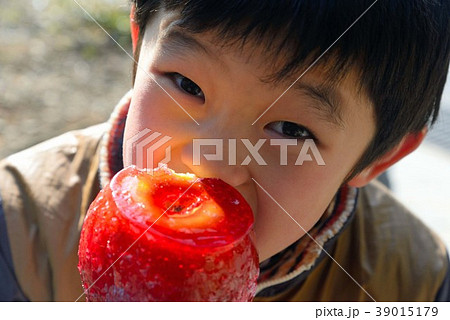 赤いリンゴ飴を舐る男の子の写真素材