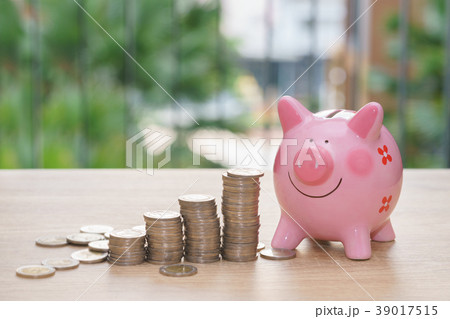 Pink piggy bank with stack coins on wooden desk Pink piggy bank with stack coins on wooden desk 39017515