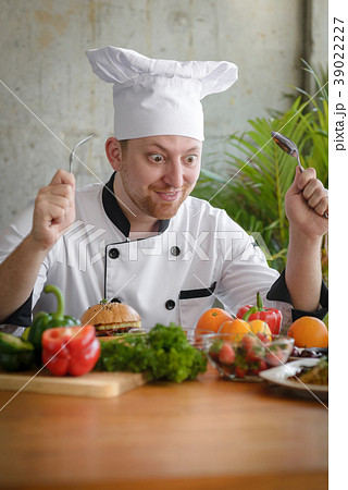 Stressed professional chef holding spoon and fork Stressed professional chef holding spoon and fork 39022227