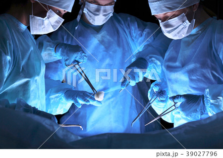 Group of surgeons in masks performing operation 39027796