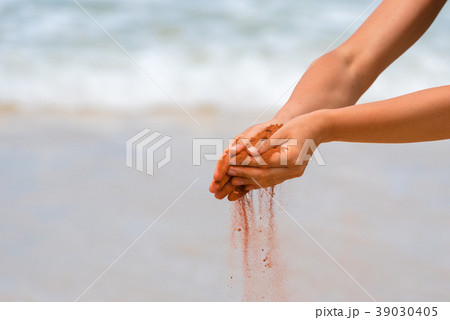 Woman hands holding red sand on the beach Woman hands holding red sand on the beach 39030405