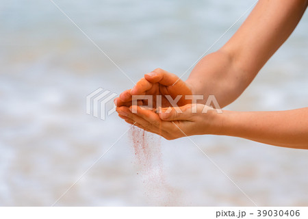 Woman hands holding red sand on the beach Woman hands holding red sand on the beach 39030406