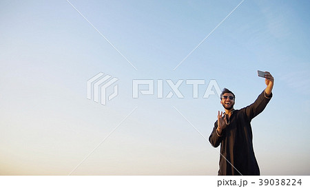 Modern male Arab traveler holds smartphone and 39038224