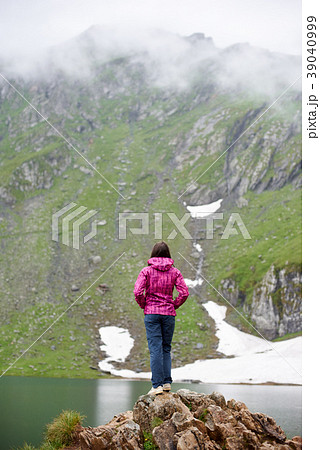 Girl hiker standing on the edge of rocky cliff. 39040999