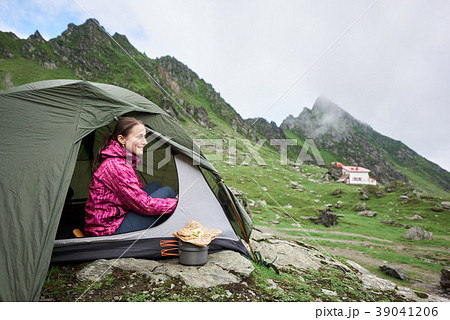 Happy tourist female sits in tent near mountain stream 39041206