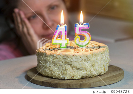 woman is not young looking at cake, candles are woman is not young looking at cake, candles are 39048728