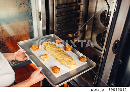 Chef puts strudel on baking sheet in the oven Chef puts strudel on baking sheet in the oven 39056015