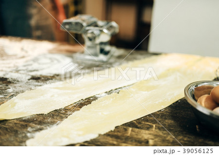 Pasta machine, dough and eggs on kitchen table Pasta machine, dough and eggs on kitchen table 39056125