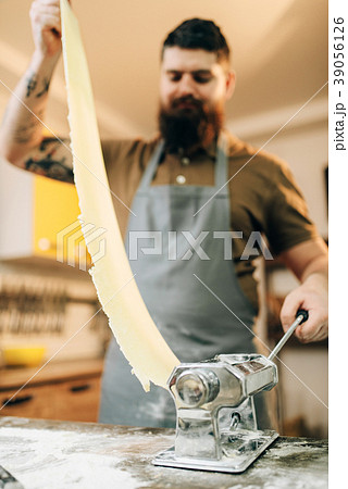 Bearded chef works with dough in pasta machine Bearded chef works with dough in pasta machine 39056126