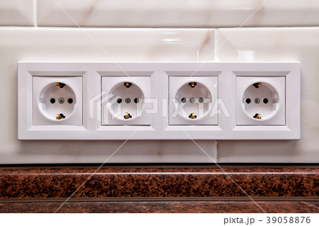 Electrical sockets on a kitchen tile wall 39058876