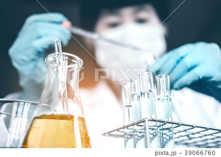 Scientist dropping chemical liquid to flask in lab Scientist dropping chemical liquid to flask in lab 39066760