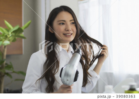 ビューティー　ドライヤーで髪を乾かしている　　若い女性 39080363