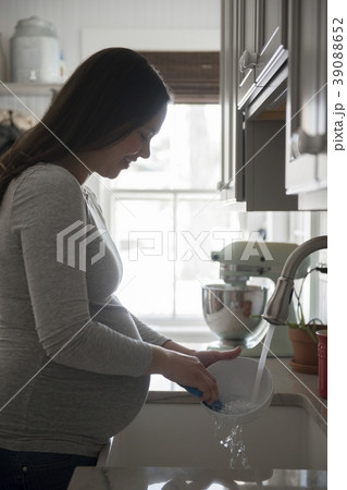 Pregnant woman washing bowl in kitchen sink Pregnant woman washing bowl in kitchen sink 39088652