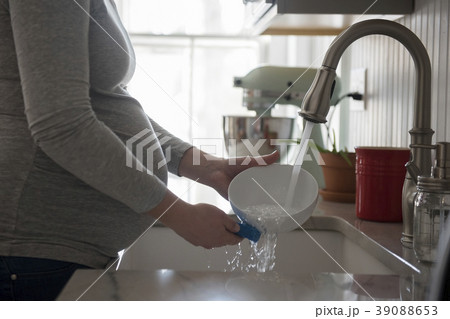 Pregnant woman washing bowl in kitchen sink, mid section 39088653