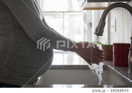 Pregnant woman washing hands in kitchen sink Pregnant woman washing hands in kitchen sink 39088654