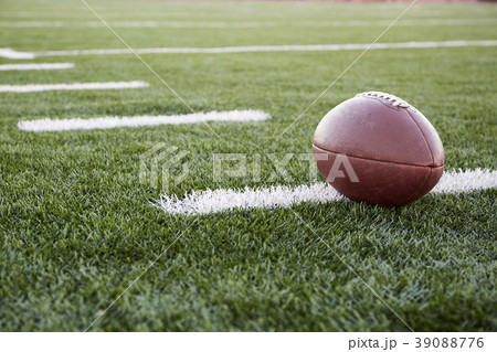 Close up of American football ball on green playing field 39088776