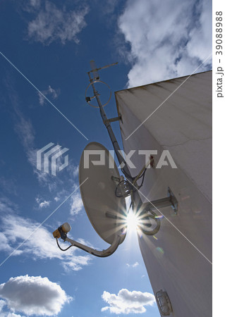 Sun shining through space between satellite dish and facade 39088988