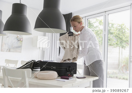 Mature woman packing suitcase at table 39089267