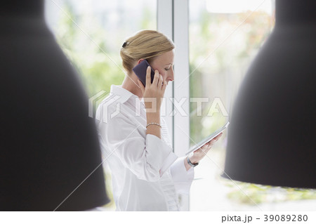 Woman talking on phone and using digital tablet Woman talking on phone and using digital tablet 39089280