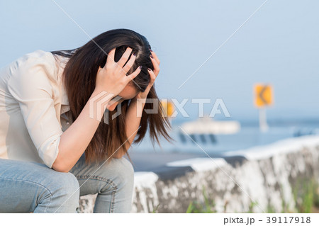 Depressed young woman sitting near a road 39117918