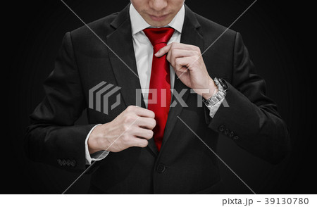 Businessman in black suit tying red necktie Businessman in black suit tying red necktie 39130780