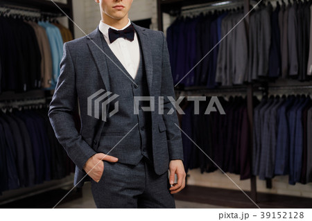 young man in classic vest against row of suits in young man in classic vest against row of suits in 39152128