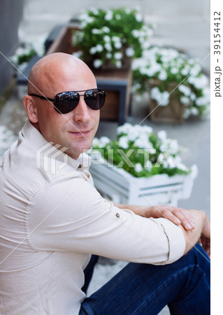 Bald man at sunglasses sit on the flowers backgrou 39154412