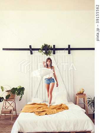 Young cheerful caucasian woman jumping on bed Young cheerful caucasian woman jumping on bed 39155562