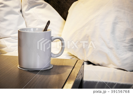 Cup of morning coffee on the bedside table in the 39156768