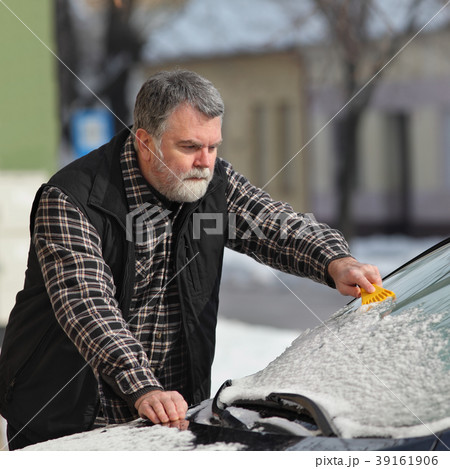 Winter scene, driver cleaning windshield of car 39161906