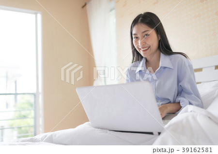 Pretty woman with laptop sitting on bed in morning Pretty woman with laptop sitting on bed in morning 39162581