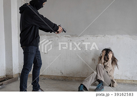 Black masked robber is aimed gun at a woman. 39162583