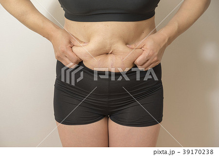 ダイエット前の女性お腹の肉をつまむの写真素材