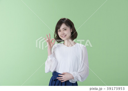 女性 ポーズ オッケー 緑背景の写真素材