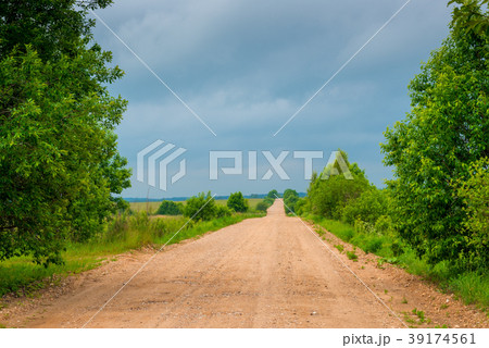 the unpaved road is empty, the sky is dark clouds 39174561