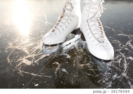 Wide skates on ice with sun reflected in behind 39176594