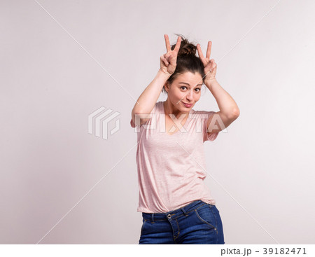 Young beautiful woman in studio making bunny ears. 39182471