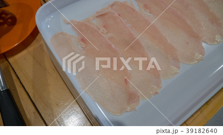 Chicken slices in white dish on wood table. 39182640