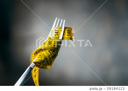 Measuring tape on a fork closeup, weight loss Measuring tape on a fork closeup, weight loss 39184123
