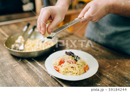 Chef grates cheese in to the plate with fettuccine Chef grates cheese in to the plate with fettuccine 39184244