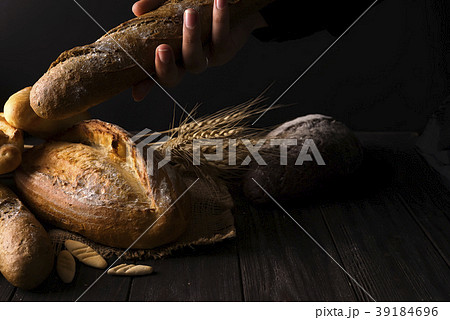 Close-up of woman hands take fresh bread. Dark 39184696