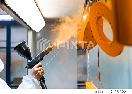 Powder coating of metal parts. A woman in a Powder coating of metal parts. A woman in a 39194089