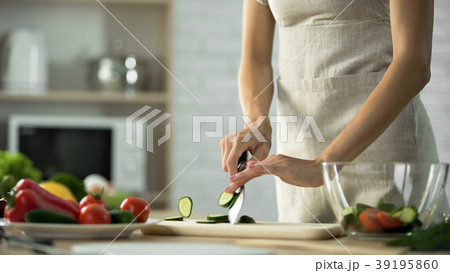 Housewife slicing fresh cucumber for dinner meal 39195860
