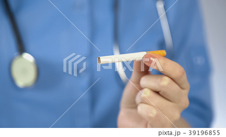 Woman doctor holding cigarette in hand, harmful Woman doctor holding cigarette in hand, harmful 39196855
